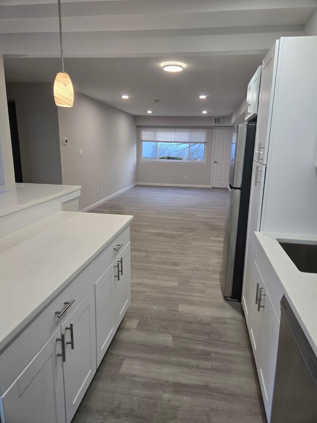 kitchen with stainless steel appliances, wood finished floors, baseboards, white cabinets, and pendant lighting