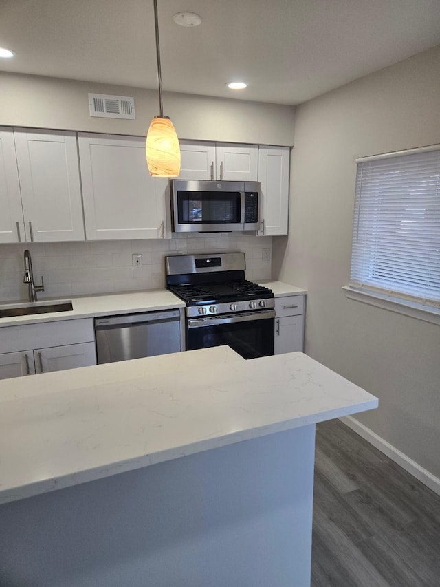 kitchen featuring dark wood-style flooring, a sink, visible vents, appliances with stainless steel finishes, and backsplash