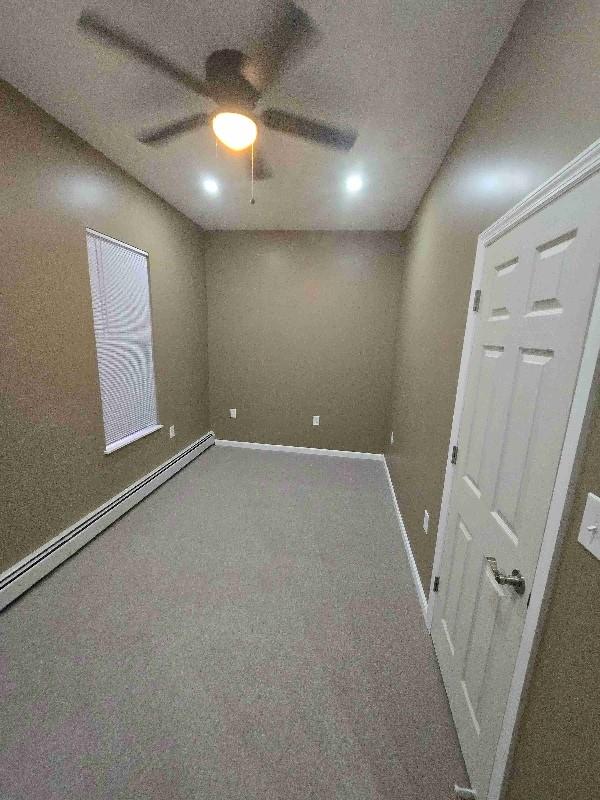 52 Lander St, Newburgh, NY 12550 - unfurnished room featuring a baseboard heating unit, a ceiling fan, baseboards, and carpet floors