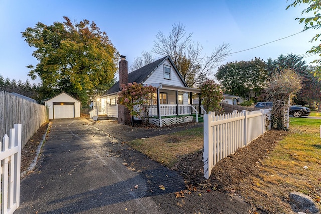 view of front of home with a garage, aphalt driveway, an outbuilding, fence, and a porch