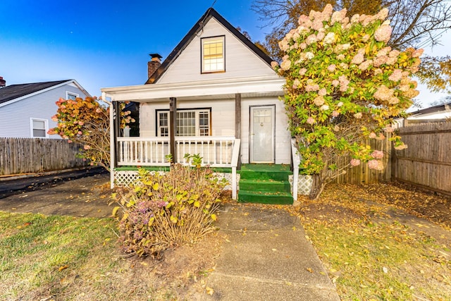 bungalow featuring a chimney, fence, and a porch