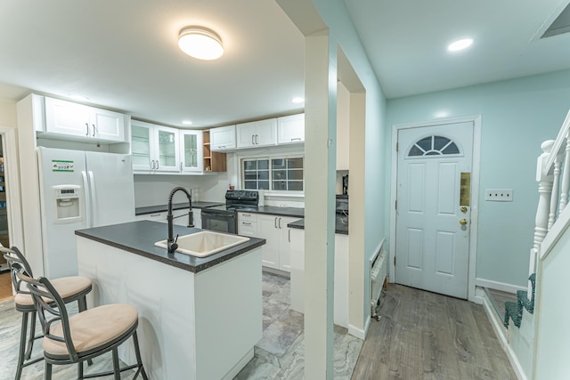 kitchen featuring white refrigerator with ice dispenser, dark countertops, a kitchen breakfast bar, black / electric stove, and a sink