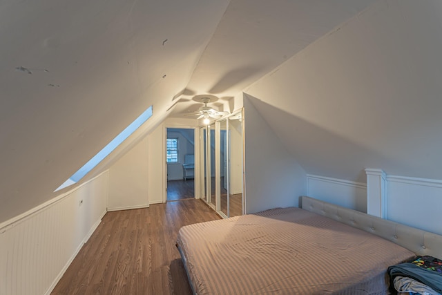 unfurnished bedroom featuring vaulted ceiling, wainscoting, and wood finished floors