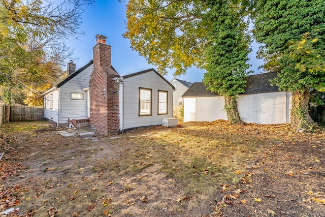 rear view of house featuring a chimney and fence