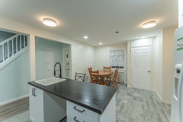 kitchen featuring dark countertops, radiator heating unit, baseboards, and a sink