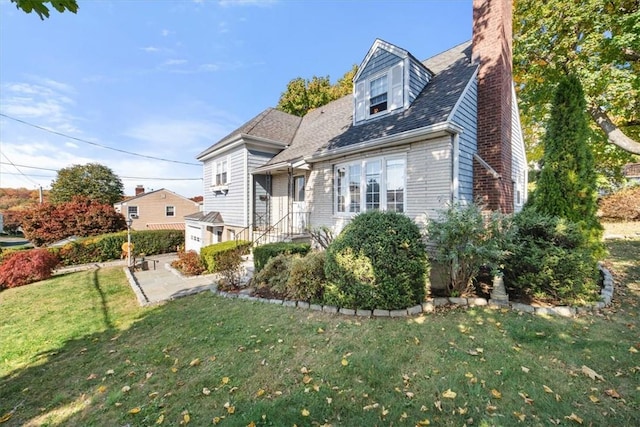 view of front of home with a patio, a chimney, and a front lawn