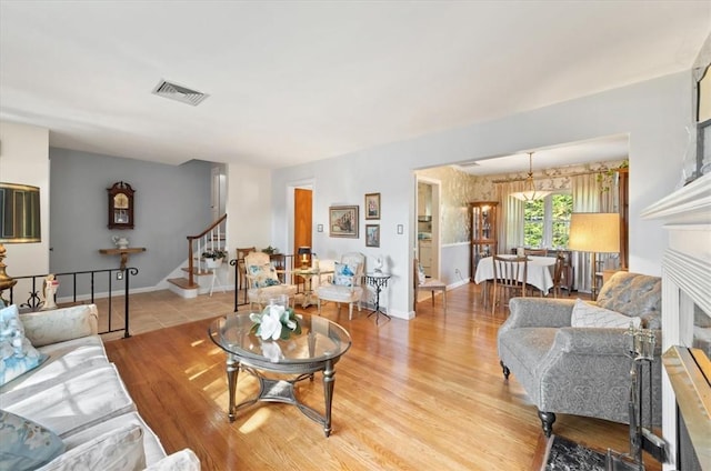 living area with stairs, baseboards, visible vents, and light wood-style floors