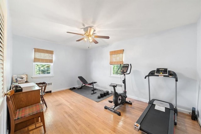 workout room featuring radiator, a ceiling fan, baseboards, and wood finished floors