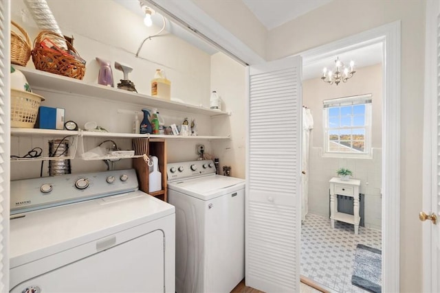 clothes washing area with a chandelier, washer and dryer, laundry area, and tile walls