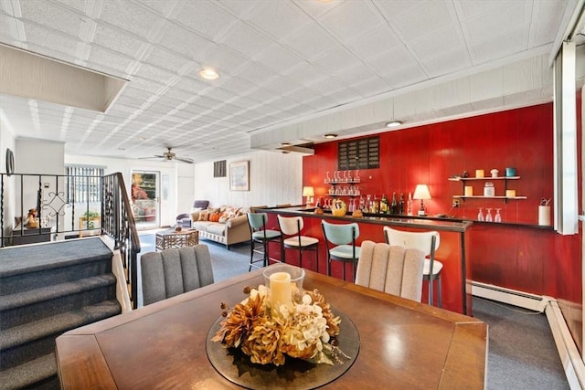 dining area with baseboard heating, carpet, a community bar, and a ceiling fan