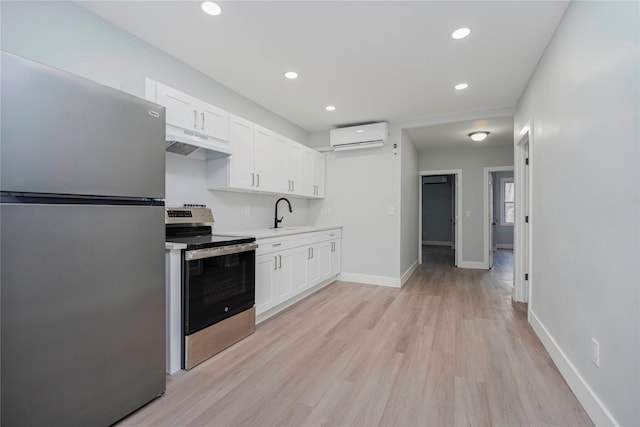 kitchen featuring an AC wall unit, under cabinet range hood, white cabinetry, appliances with stainless steel finishes, and light countertops