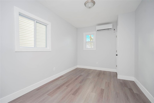 unfurnished room with an AC wall unit, baseboards, and wood finished floors