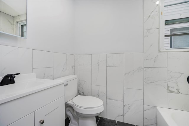 bathroom featuring toilet, tile walls, and vanity