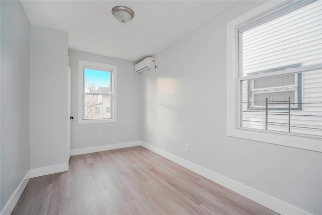 empty room with light wood-type flooring, baseboards, and a wall unit AC