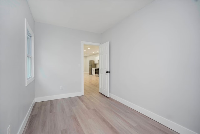 spare room featuring recessed lighting, light wood-type flooring, and baseboards