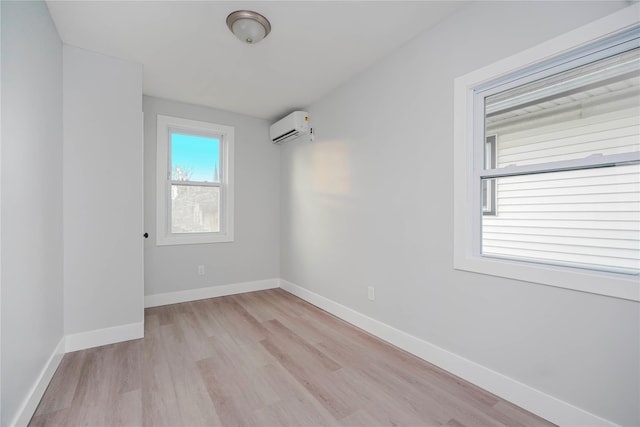 spare room featuring light wood-style floors, a wall mounted AC, and baseboards