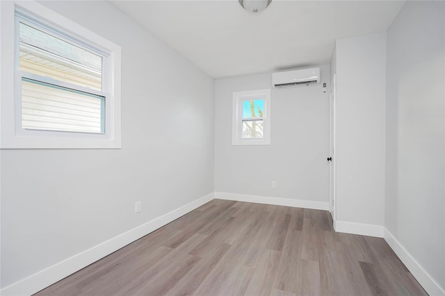 spare room featuring wood finished floors, baseboards, and a wall mounted AC