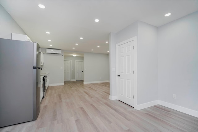 interior space with a wall mounted air conditioner, light wood-type flooring, recessed lighting, freestanding refrigerator, and white cabinetry