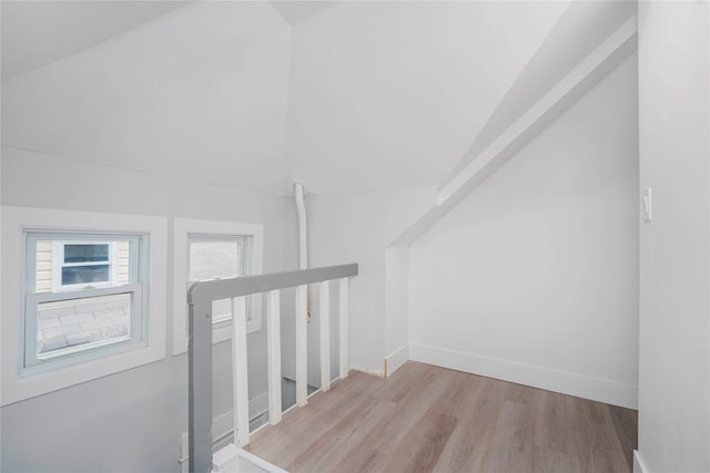 interior space featuring baseboards, wood finished floors, and vaulted ceiling