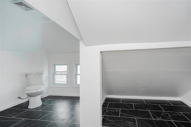 bathroom with visible vents, lofted ceiling, toilet, and baseboards