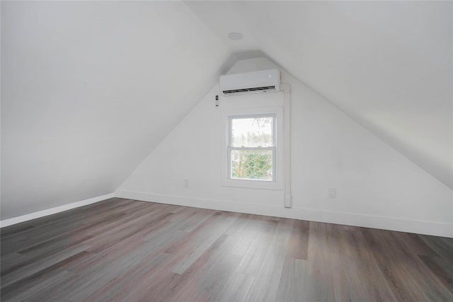 bonus room featuring vaulted ceiling, a wall mounted AC, baseboards, and wood finished floors