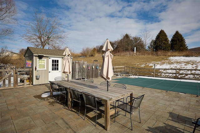 view of pool featuring an outbuilding, outdoor dining area, a patio area, and fence