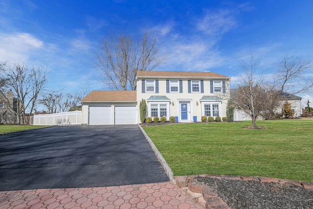 colonial inspired home with a garage, driveway, a front lawn, and fence