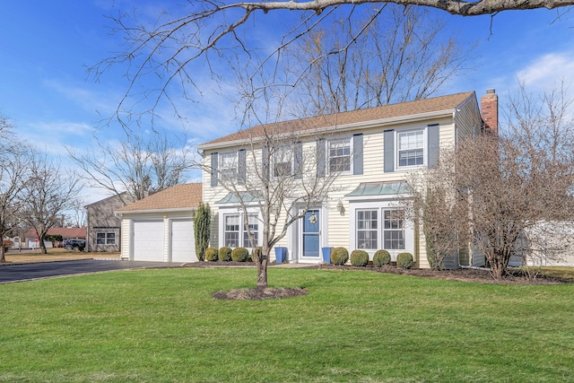 colonial home featuring aphalt driveway, a front lawn, a chimney, and an attached garage