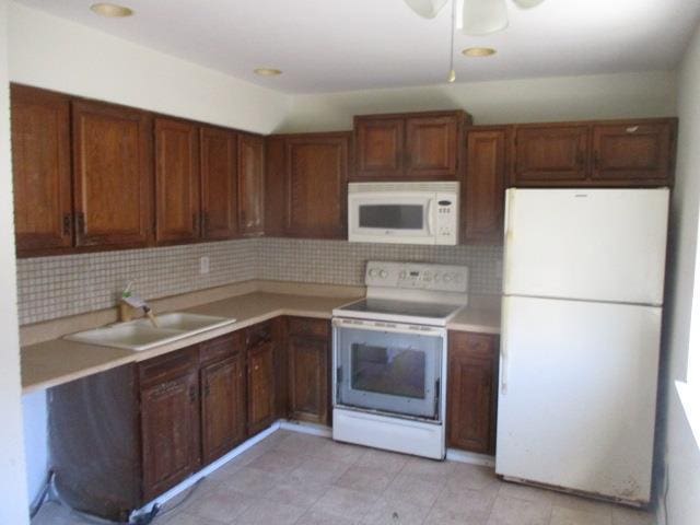 kitchen with light countertops, white appliances, a sink, and tasteful backsplash