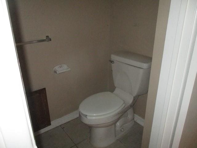 bathroom with baseboards, toilet, and tile patterned floors