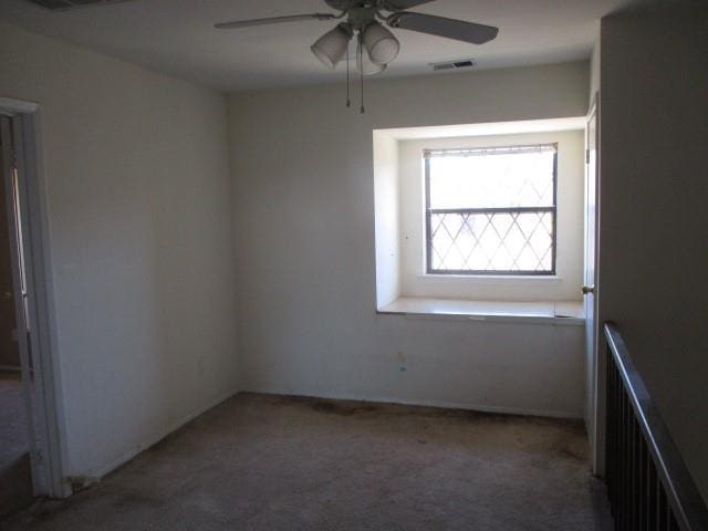 carpeted empty room featuring radiator heating unit, visible vents, and a ceiling fan