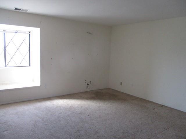 carpeted empty room featuring visible vents