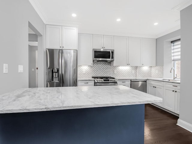 kitchen featuring dark wood finished floors, light stone countertops, stainless steel appliances, crown molding, and a sink