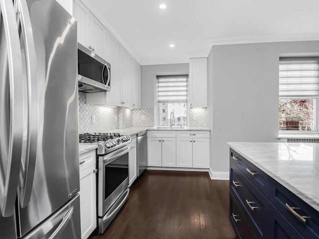 kitchen featuring stainless steel appliances, white cabinetry, light stone countertops, plenty of natural light, and dark wood finished floors