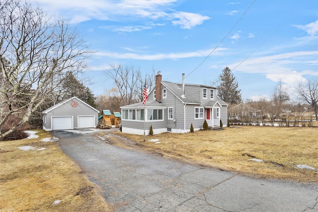 view of front of property with a garage, entry steps, a chimney, an outdoor structure, and a front yard