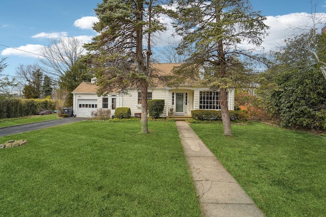 view of front of property featuring aphalt driveway, an attached garage, a front yard, and a shingled roof