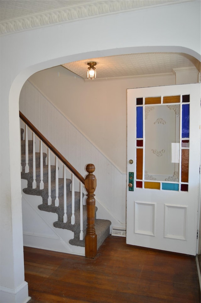 foyer entrance featuring a wainscoted wall, arched walkways, wood finished floors, and stairway