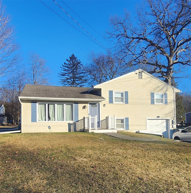 tri-level home featuring a garage, a shingled roof, and a front yard