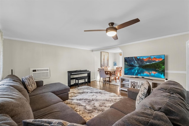 living area with arched walkways, ornamental molding, ceiling fan, and wood finished floors