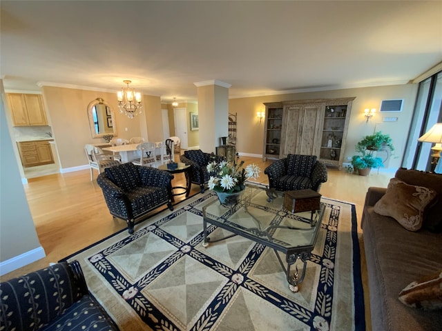 living area with light wood-type flooring, a chandelier, and ornamental molding