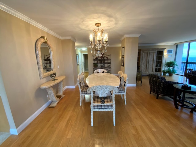 dining space with a chandelier, baseboards, wood finished floors, and crown molding