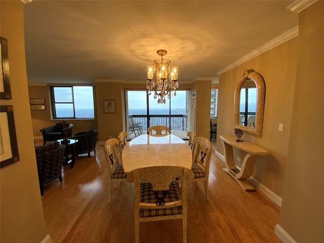 dining space with ornamental molding, wood finished floors, a wealth of natural light, and an inviting chandelier