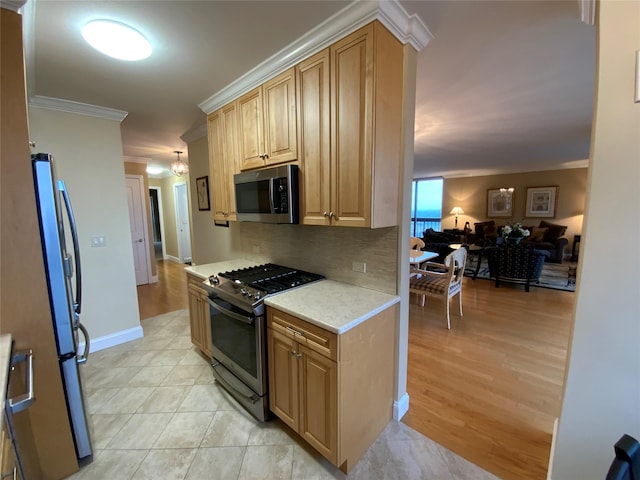 kitchen with light countertops, backsplash, appliances with stainless steel finishes, ornamental molding, and open floor plan