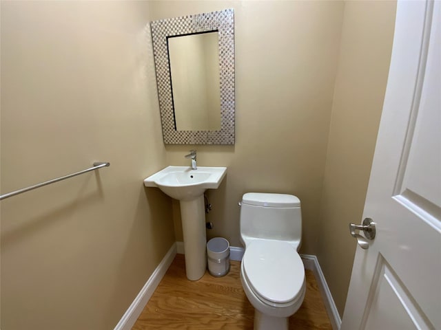 half bath featuring toilet, baseboards, and wood finished floors