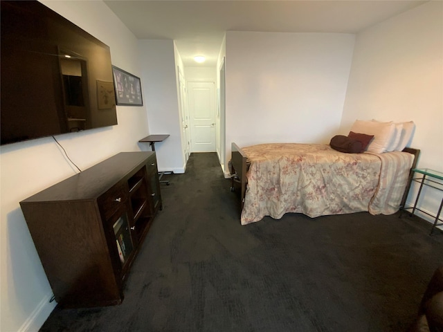 bedroom featuring dark carpet and baseboards