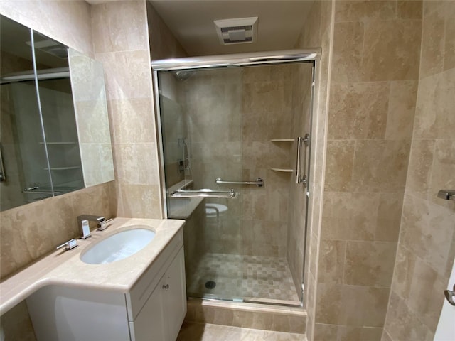 full bathroom featuring a shower stall, visible vents, tile walls, and vanity