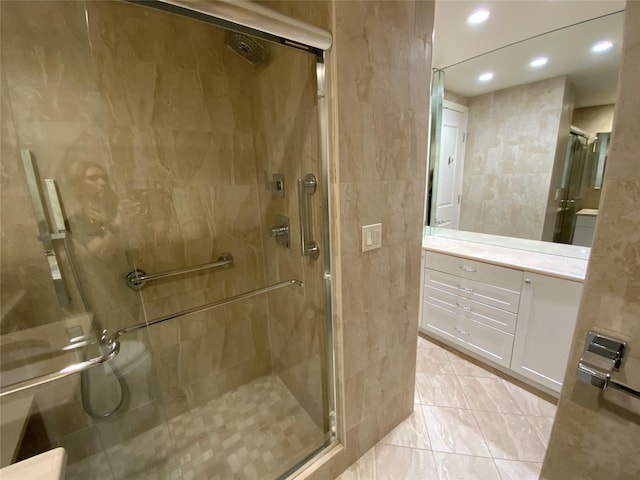 bathroom featuring a stall shower, recessed lighting, vanity, and tile walls