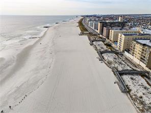 bird's eye view with a water view and a beach view