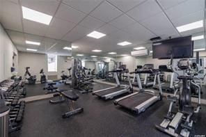 gym featuring a wall mounted air conditioner and a drop ceiling