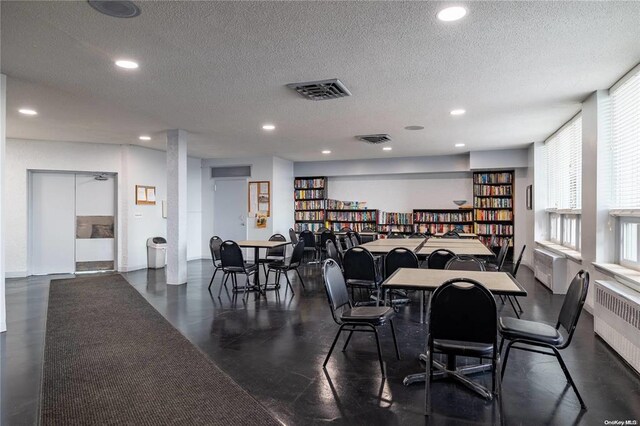 dining room with radiator heating unit, visible vents, a textured ceiling, and recessed lighting